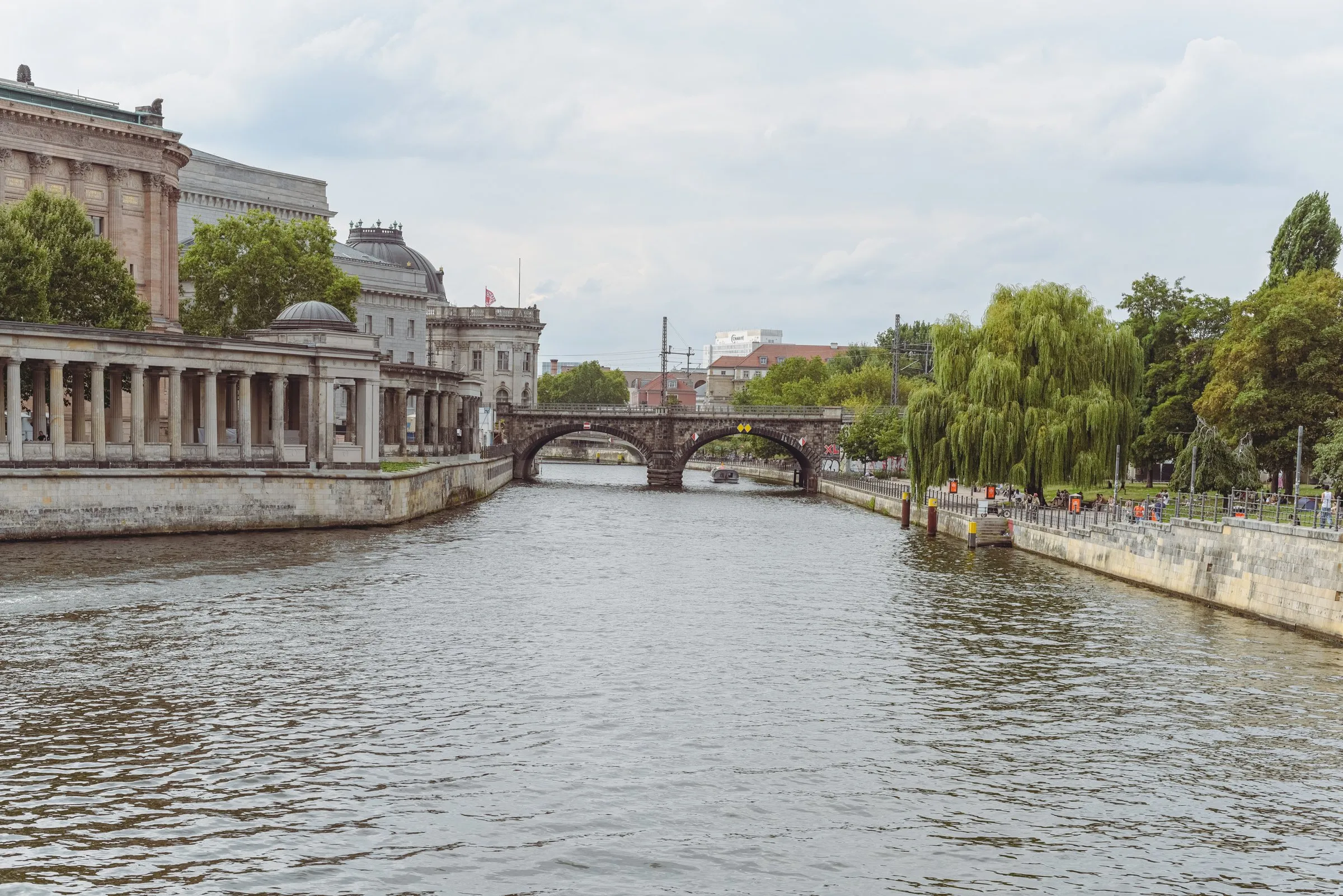 The Spree at Museum Island in Berlin, with the colonnades and museum buildings on the left bank, the arched Stadtbahn railway bridge ahead and weeping willows on the right bank