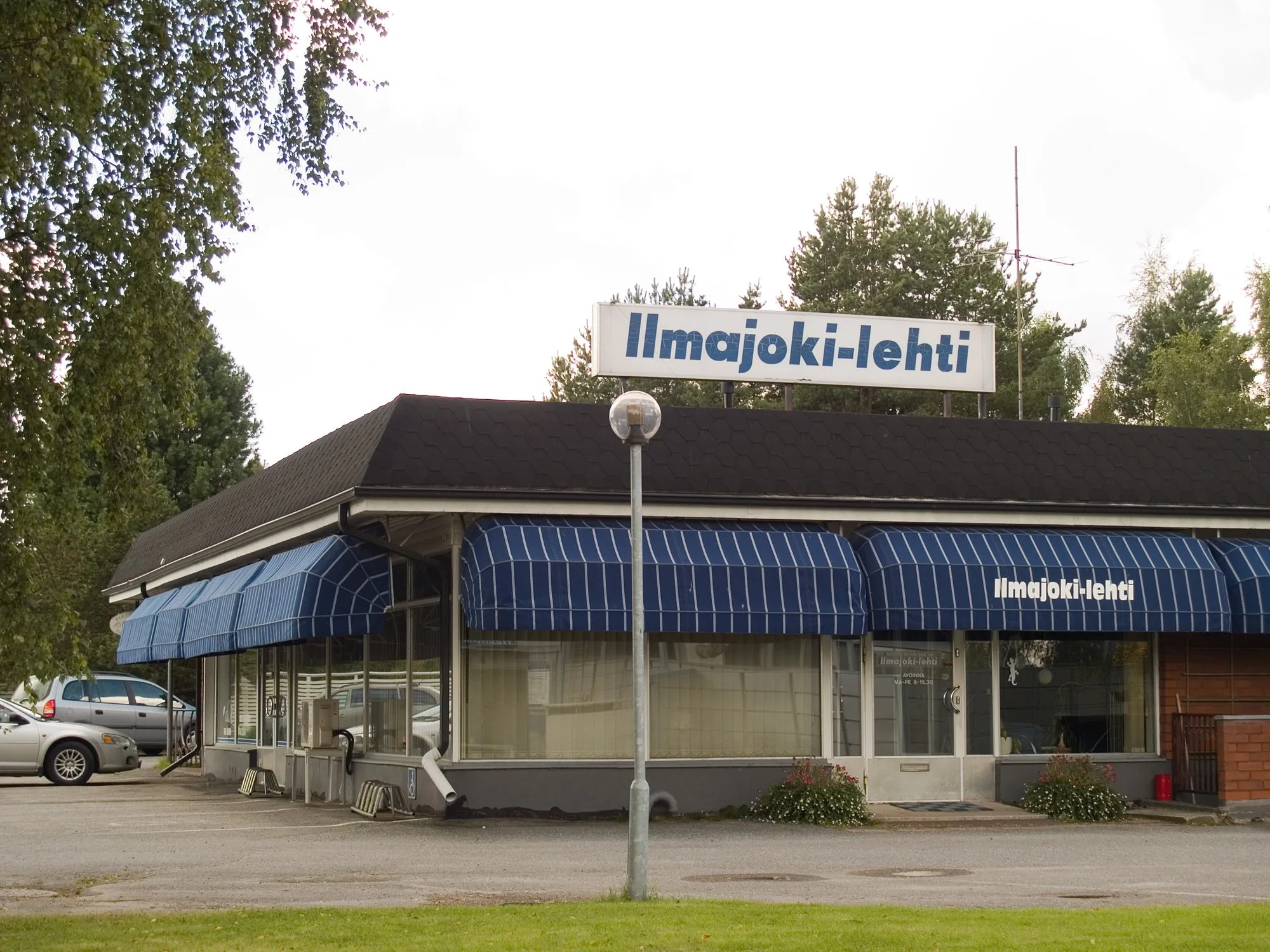 Redacția cu un singur nivel a ziarului local Ilmajoki-lehti din Ilmajoki, Finlanda, cu titlul publicației pe o firmă deasupra copertinelor cu dungi albastre