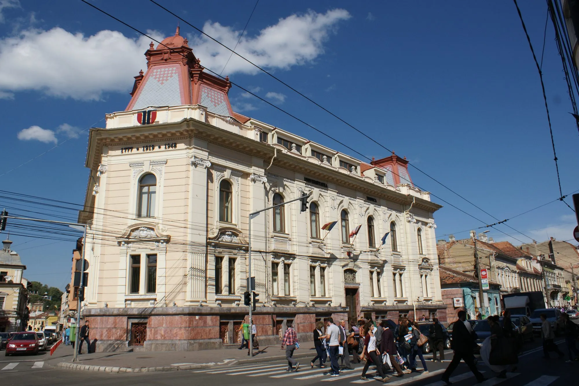 The rectorate building of the Technical University of Cluj-Napoca, a cream-coloured corner building with two red-roofed towers, seen from the street